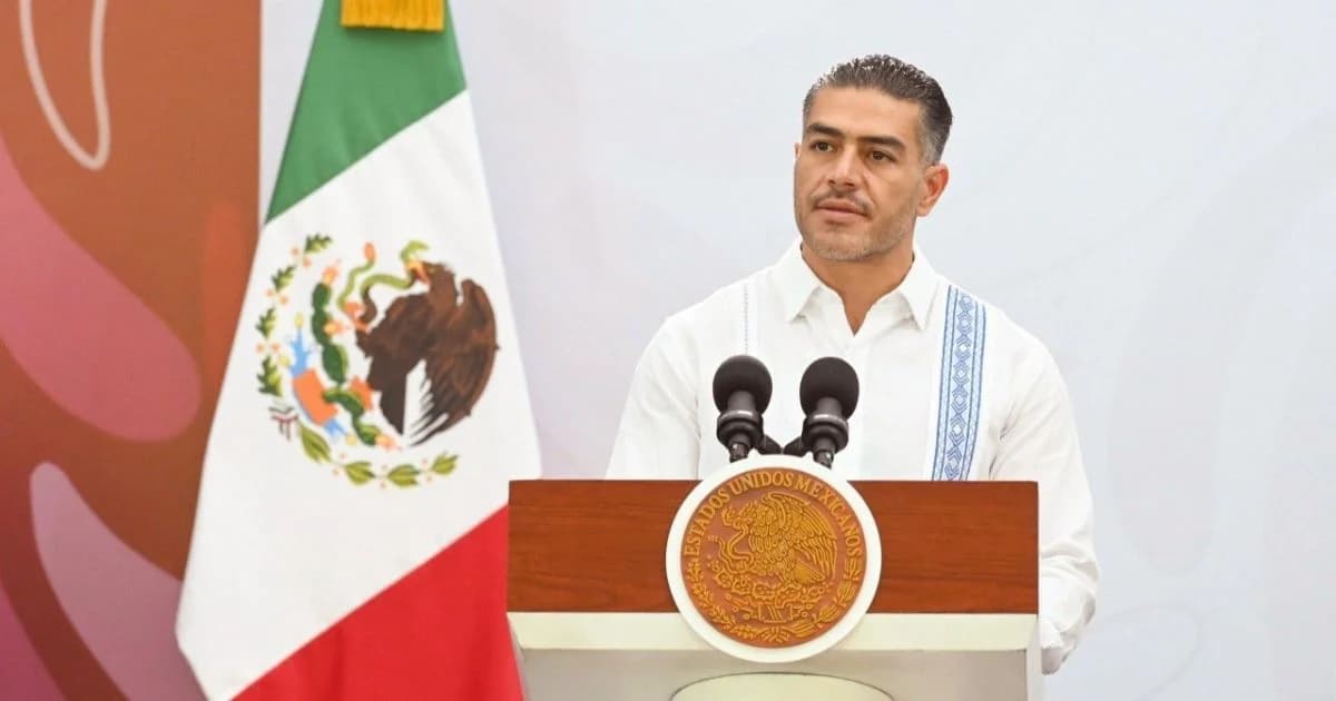 Funcionario federal durante una conferencia sobre seguridad en Chiapas, frente a la bandera de México