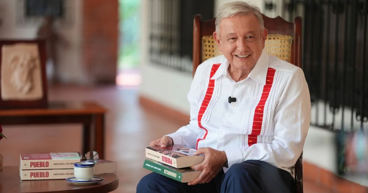 Andrés Manuel López Obrador sentado con ejemplares de Pueblo y Grandeza
