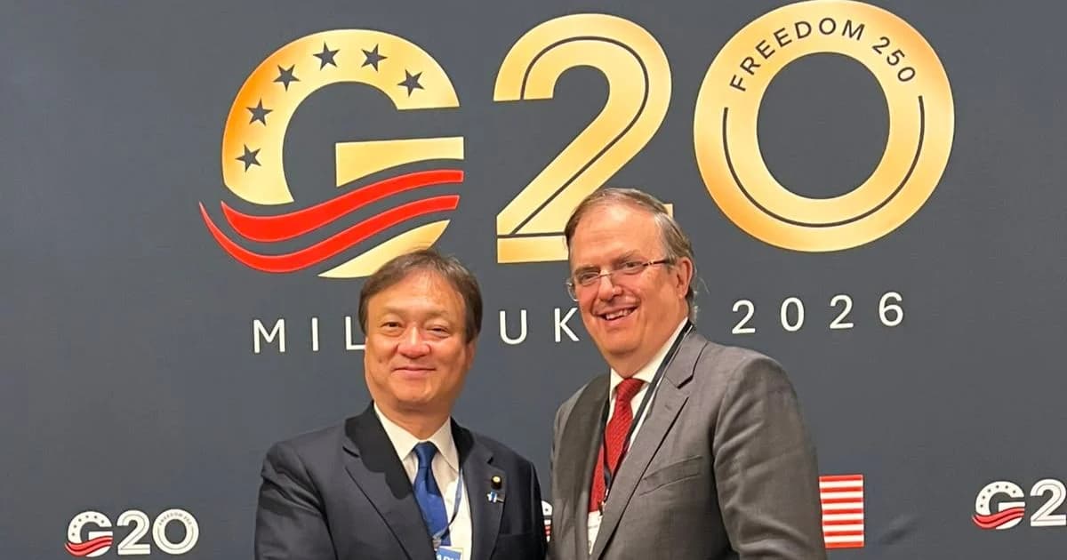 Marcelo Ebrard estrecha la mano de un funcionario japonés frente al emblema del G20 en Milwaukee