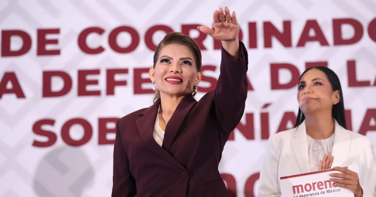 Mujer levanta la mano durante un acto político junto a un nombramiento de Morena