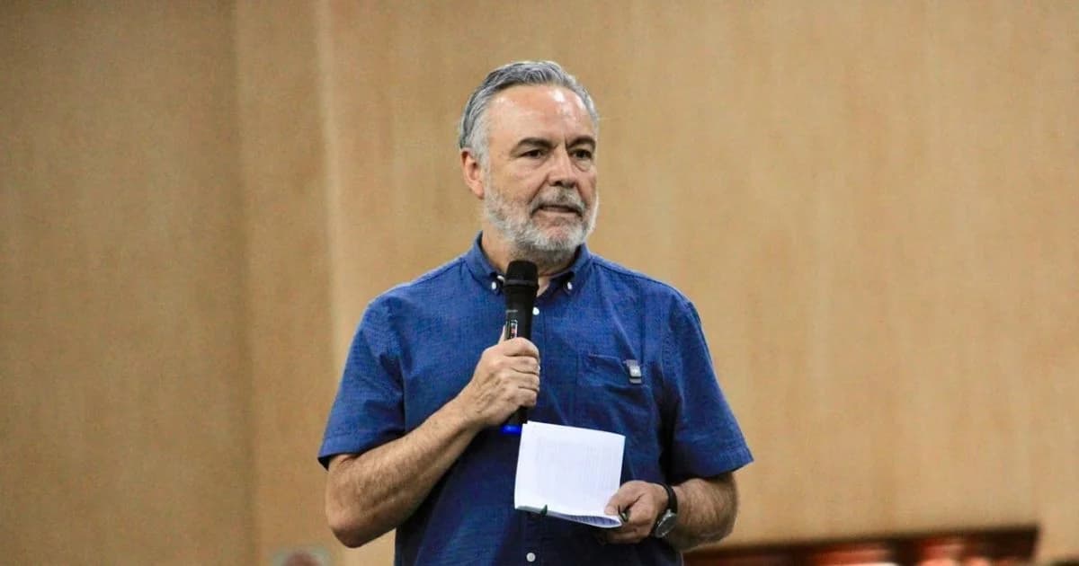 Alfonso Ramírez Cuéllar habla frente a un micrófono y sostiene unas hojas durante un encuentro