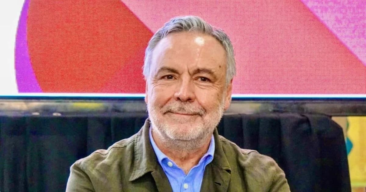 Retrato de un hombre de cabello canoso y barba con camisa azul y saco verde