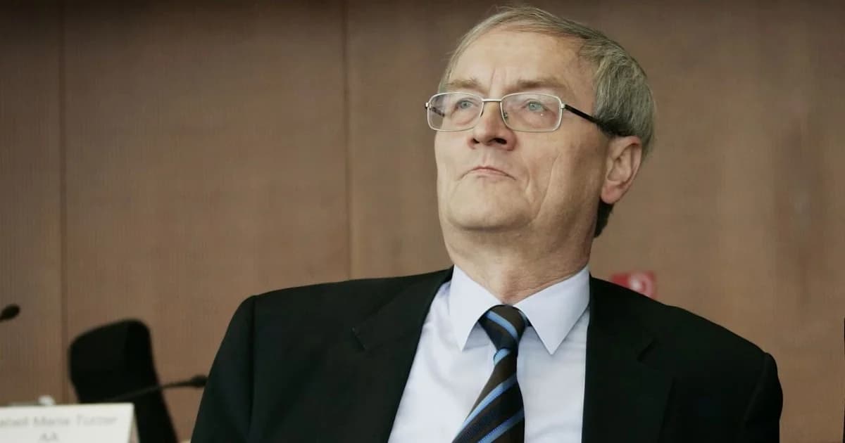 Hombre de traje y corbata con lentes durante una comparecencia pública