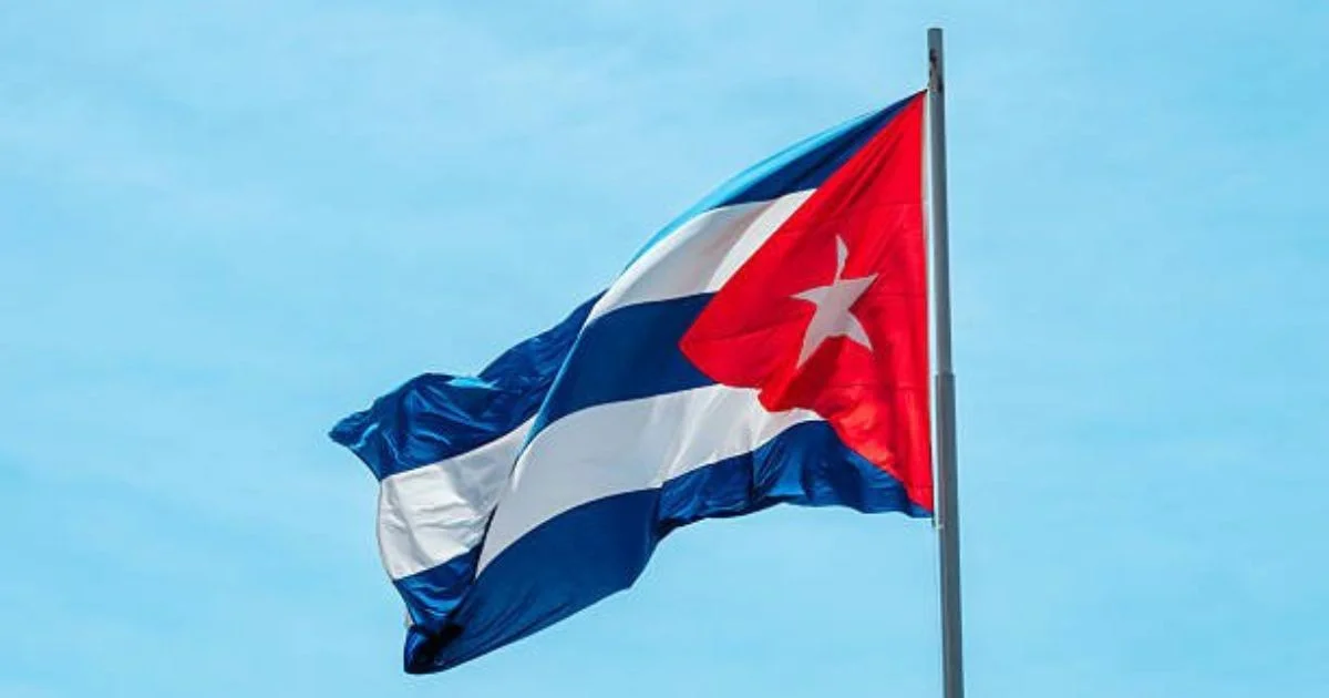 Bandera nacional cubana desplegada sobre un fondo de cielo azul.