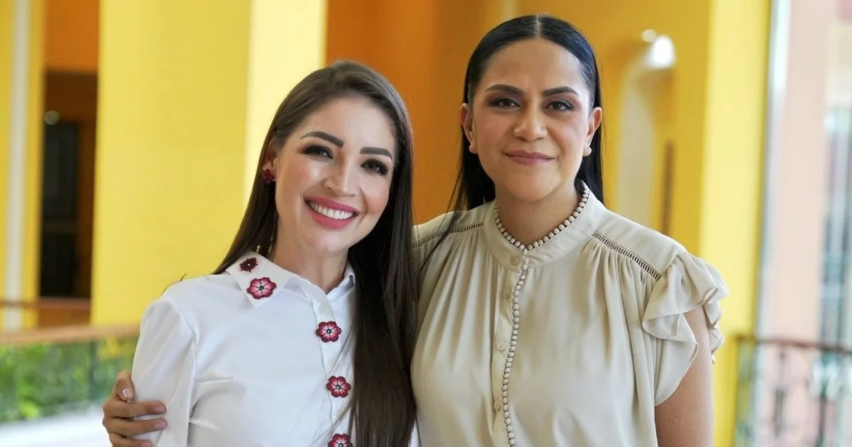 Jasmine Bugarín y Ariadna Montiel posan juntas frente a una pared amarilla, tomadas del hombro