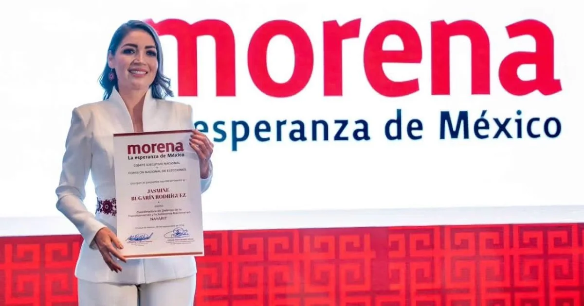 Mujer sostiene una constancia frente a una pantalla con el logotipo de Morena