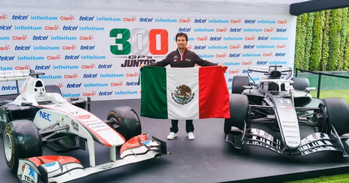 Checo Pérez con la bandera de México en una presentación entre dos autos de carreras