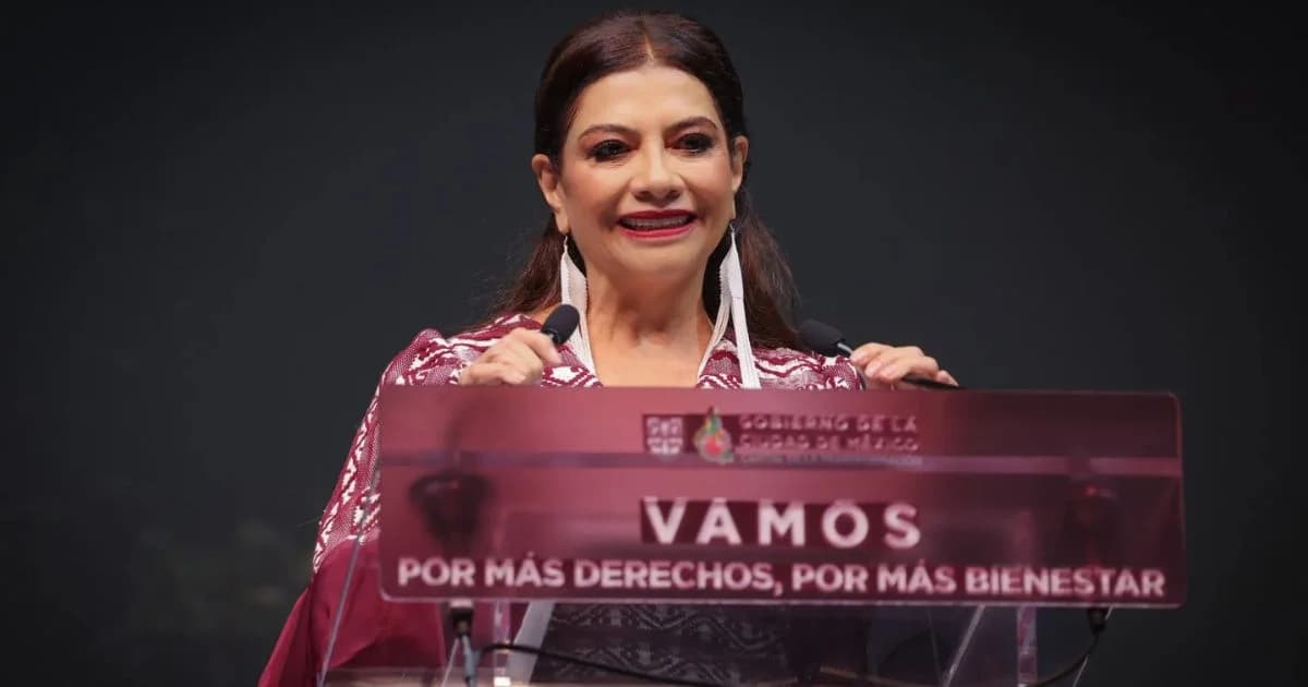 Mujer habla ante dos micrófonos desde un atril con la frase Vamos por más derechos, por más bienestar