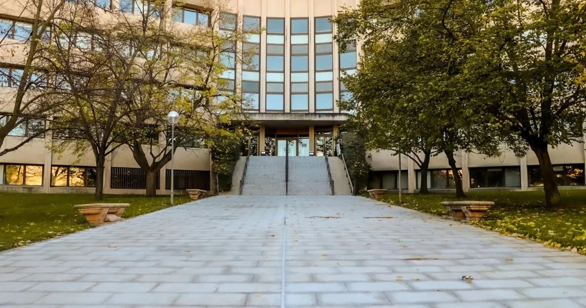 Fachada de un edificio institucional rodeado de árboles