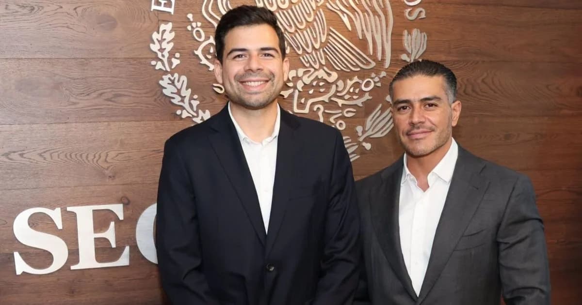 Manuel Cota Cárdenas y Omar García Harfuch posan frente al escudo nacional en una pared de madera