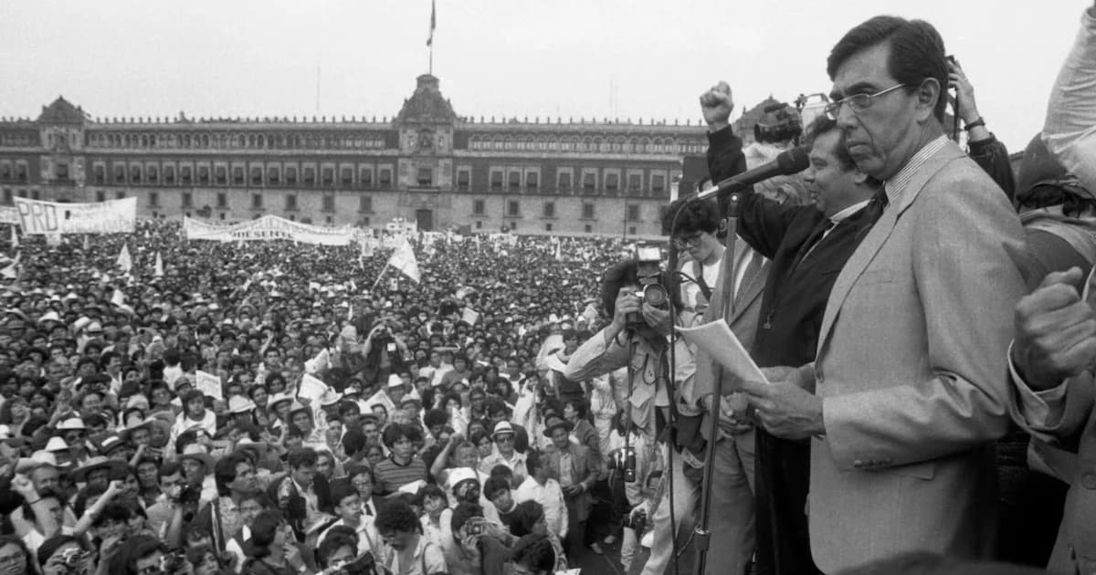Fotografía histórica en blanco y negro de un orador con documentos frente a un micrófono, ante una multitud reunida en el Zócalo de Ciudad de México.