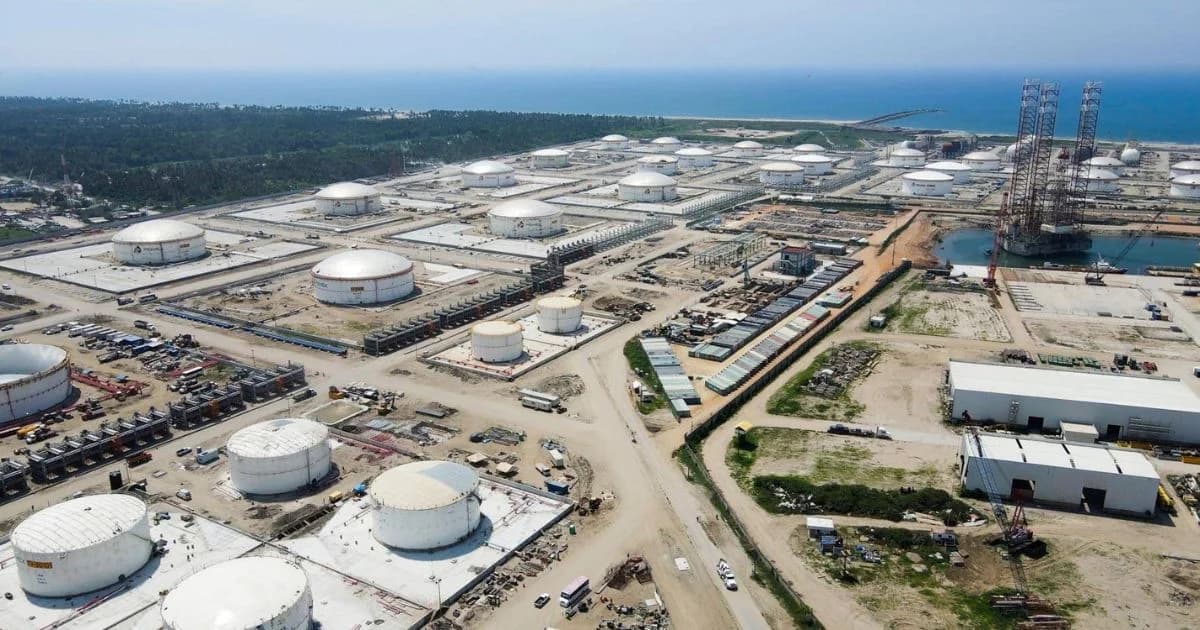 Vista aérea de un complejo industrial costero con numerosos tanques cilíndricos de almacenamiento, tuberías y estructuras