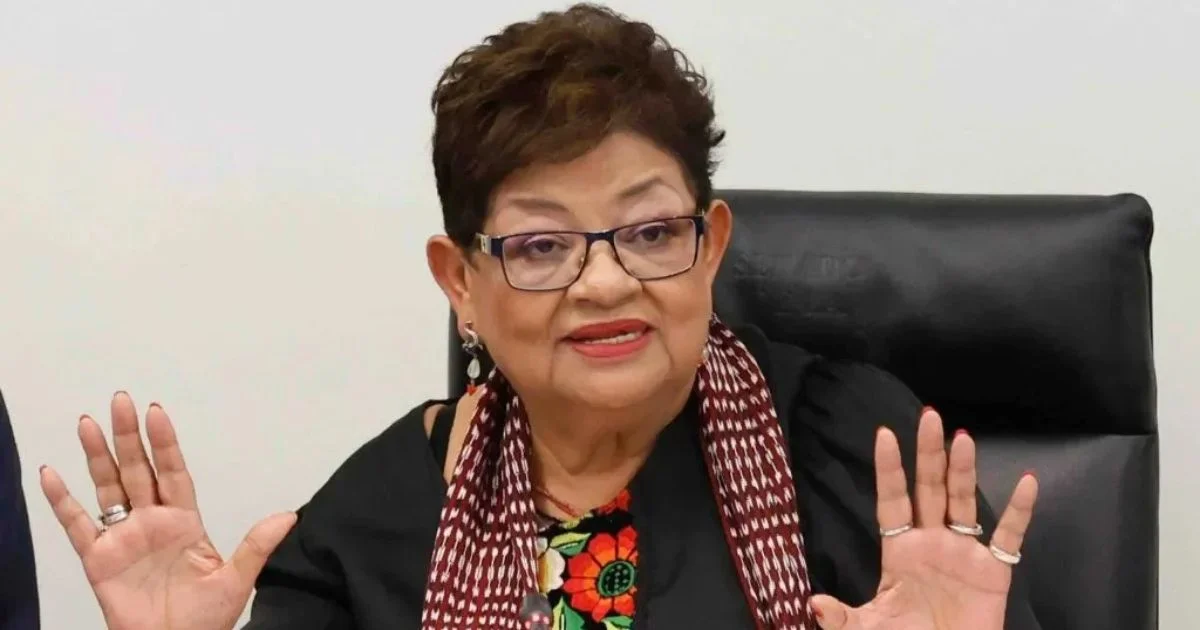 Ernestina Godoy habla sentada ante un micrófono y levanta ambas manos