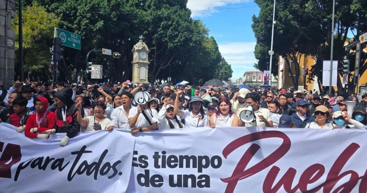 Contingente ciudadano sostiene una manta en una marcha por el Centro Histórico de Puebla