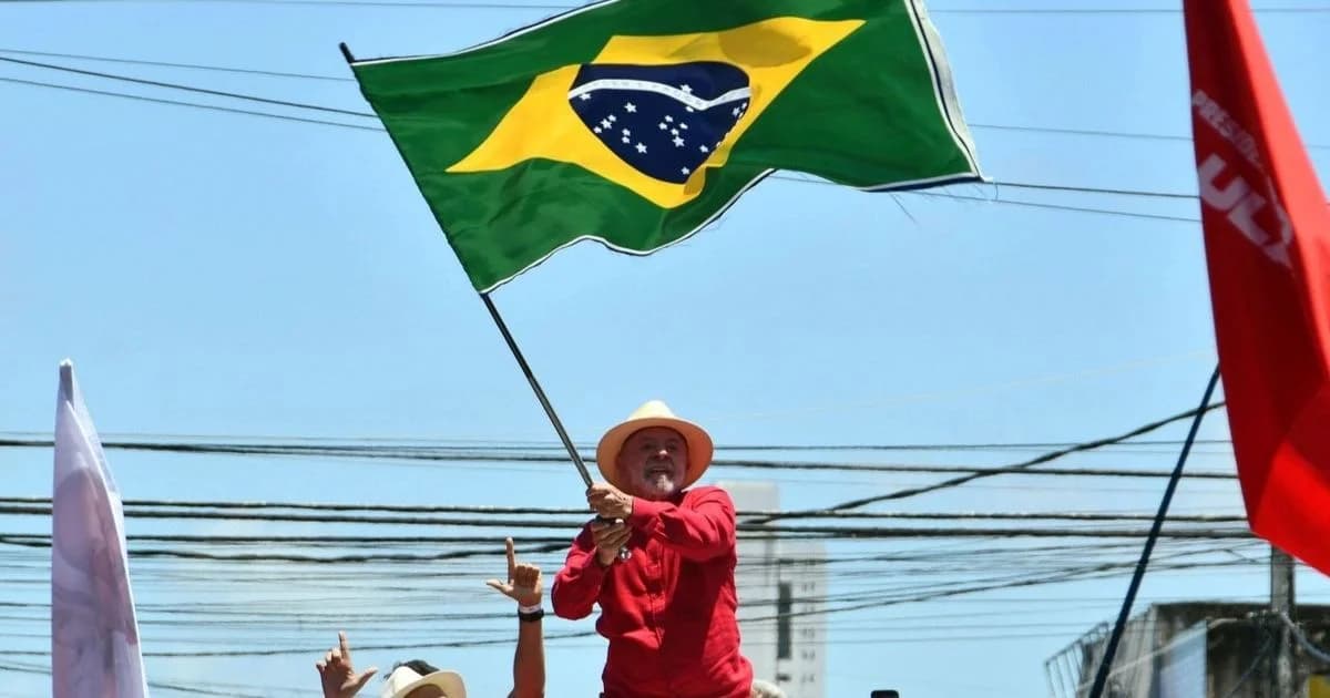 Persona con camisa roja y sombrero ondea una bandera de Brasil durante una concentración al aire libre