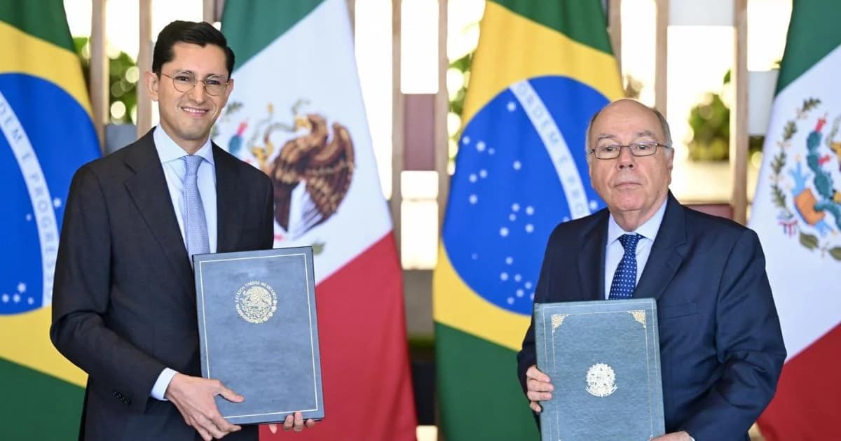 Dos funcionarios sostienen carpetas frente a banderas de México y Brasil