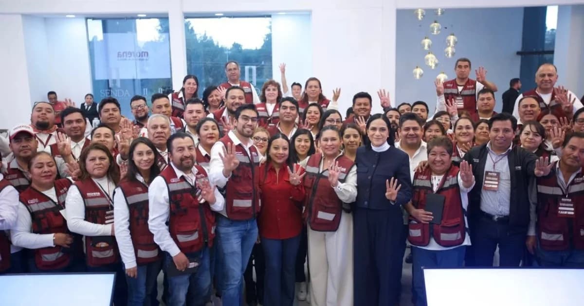 Integrantes de Morena posan para una fotografía grupal en un espacio interior, algunos con chalecos guinda del partido y las manos levantadas