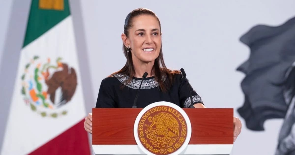 Claudia Sheinbaum durante un mensaje desde un podio con el Escudo Nacional y la bandera de México al fondo