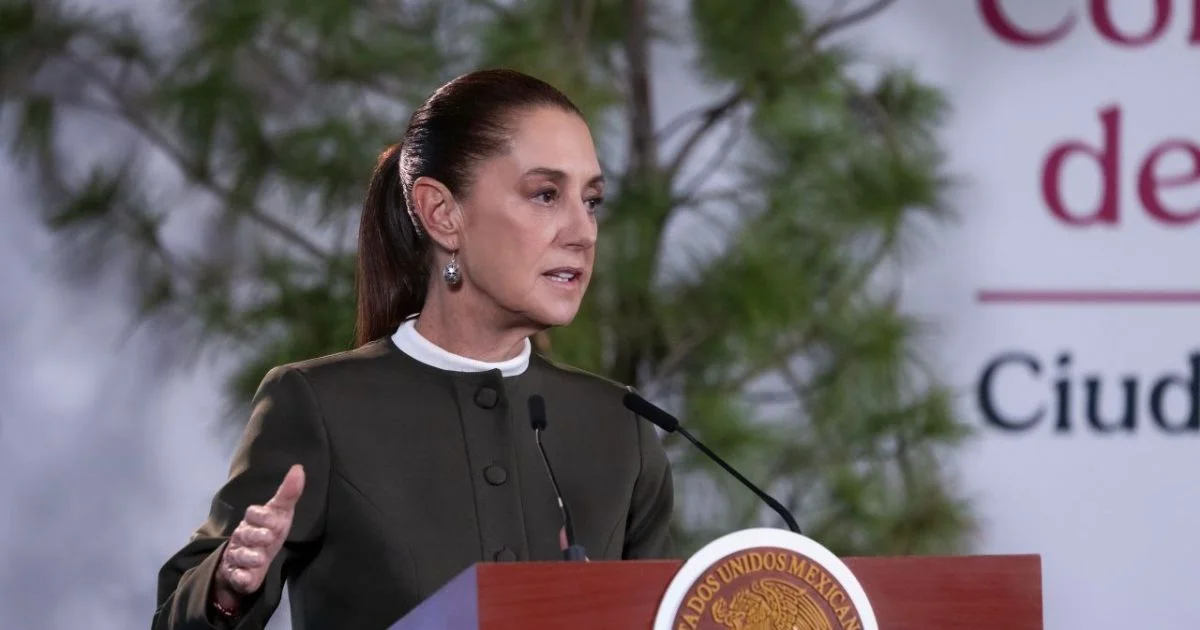 Claudia Sheinbaum habla ante micrófonos desde un podio con el escudo nacional.