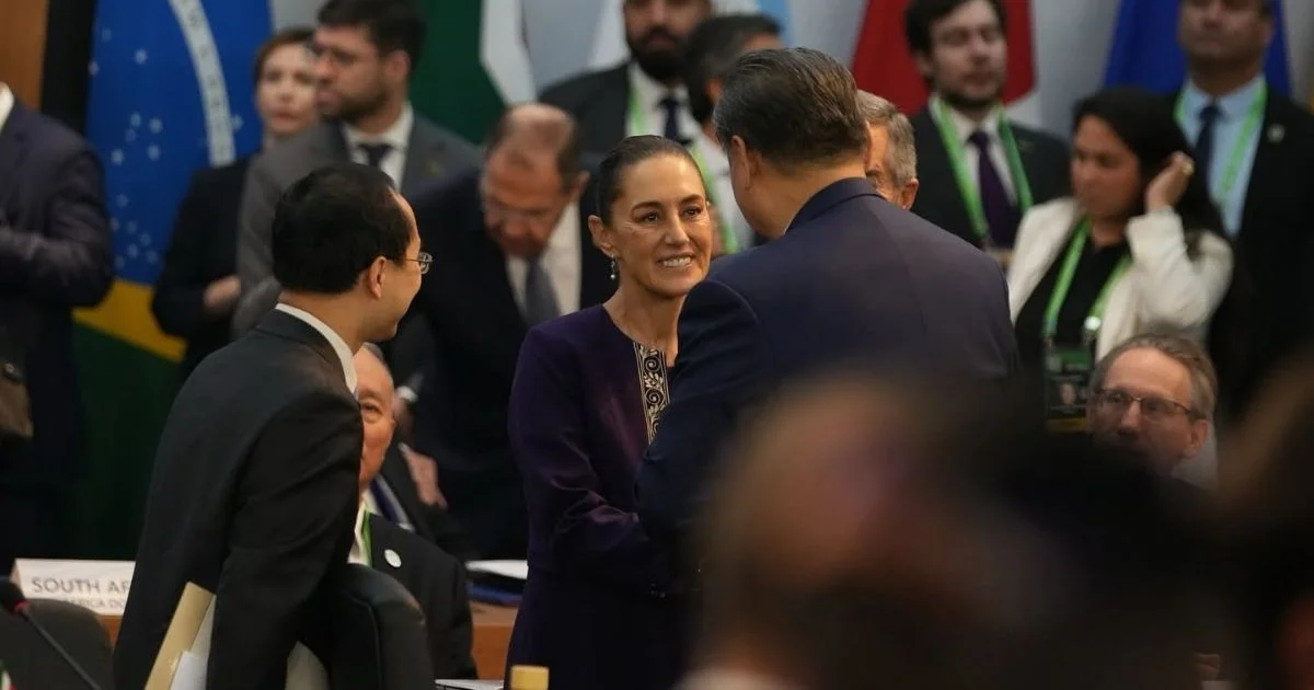 Claudia Sheinbaum conversa con Xi Jinping en una reunión internacional, rodeados de asistentes y representantes diplomáticos