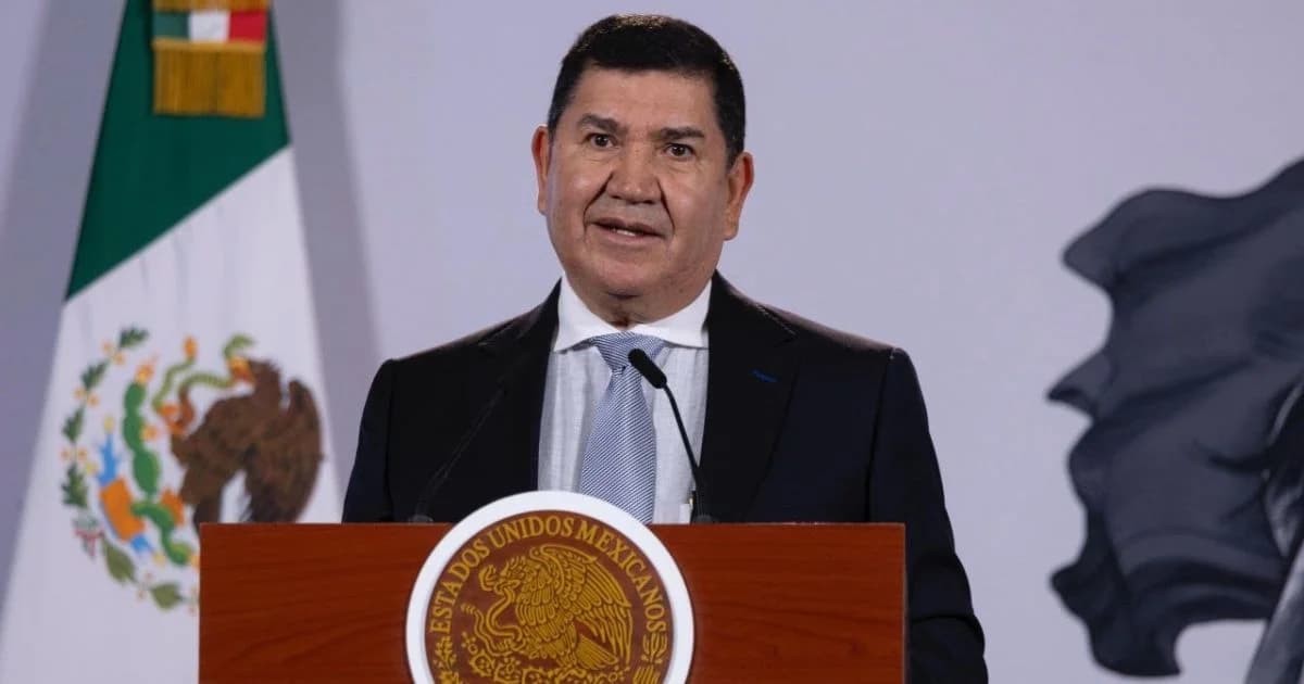 Un funcionario habla ante un podio con el escudo nacional y la bandera de México durante una conferencia de prensa.