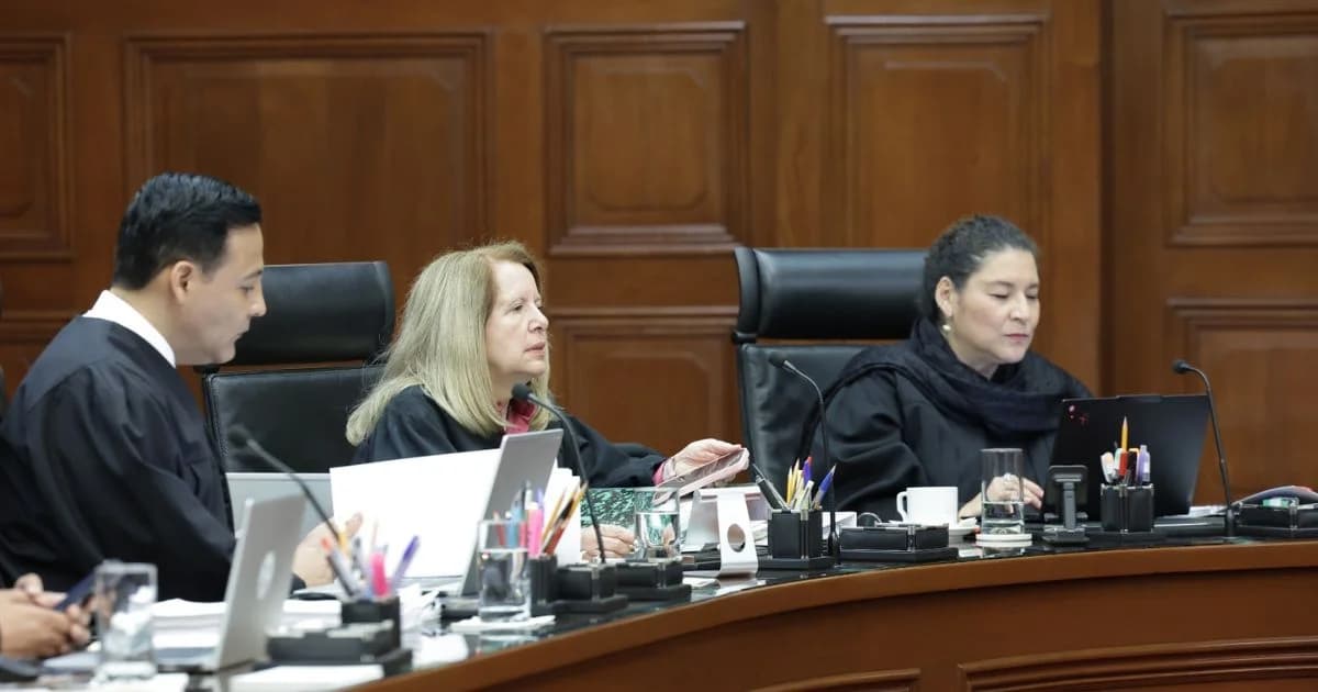 Tres personas con vestimenta judicial participan en una sesión de tribunal frente a computadoras y micrófonos