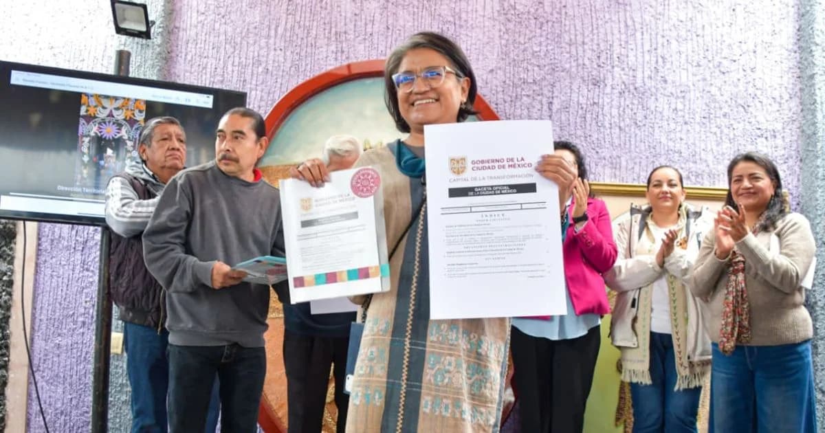 Mujer sostiene dos documentos ante vecinos durante una ceremonia en Iztapalapa