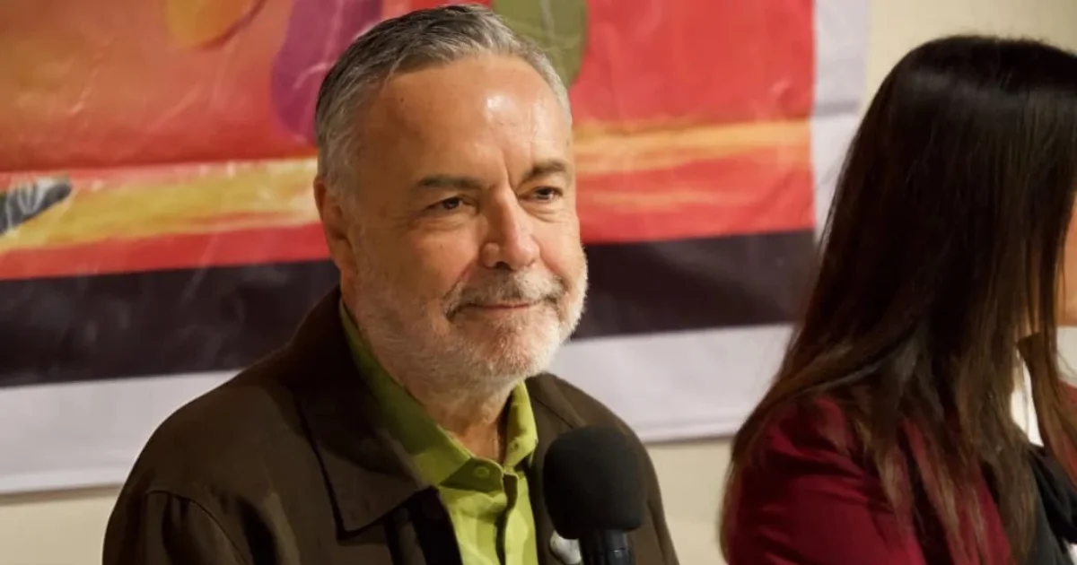 Alfonso Ramírez Cuéllar aparece sentado con micrófono durante un encuentro público.