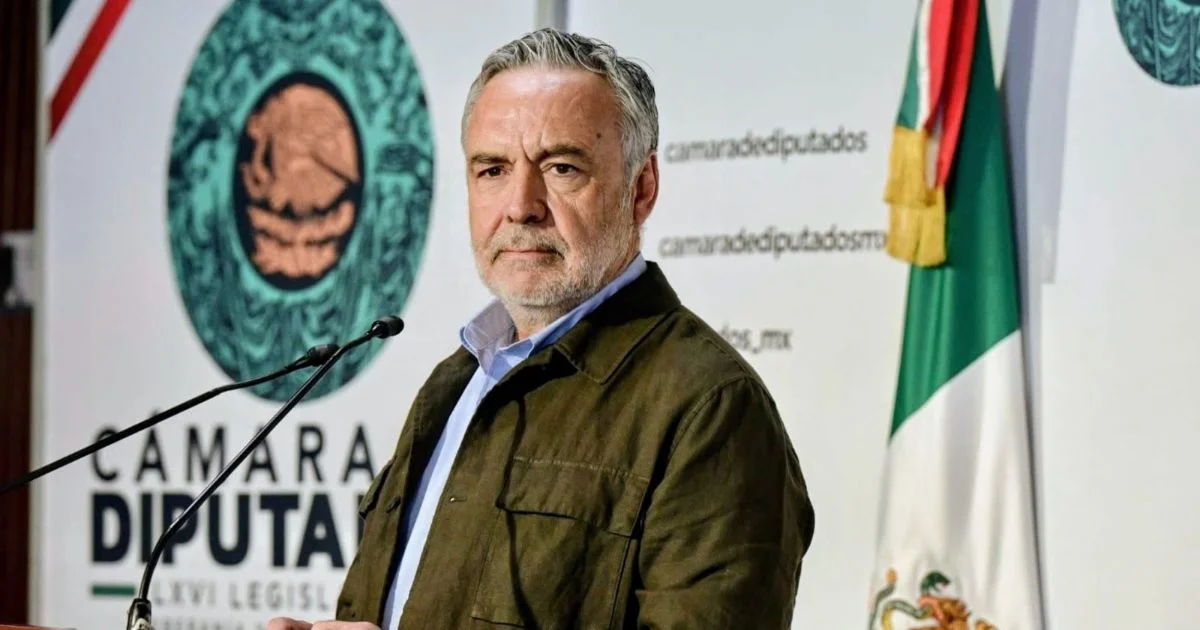 Alfonso Ramírez Cuéllar frente a micrófonos en la Cámara de Diputados, con la bandera de México al fondo