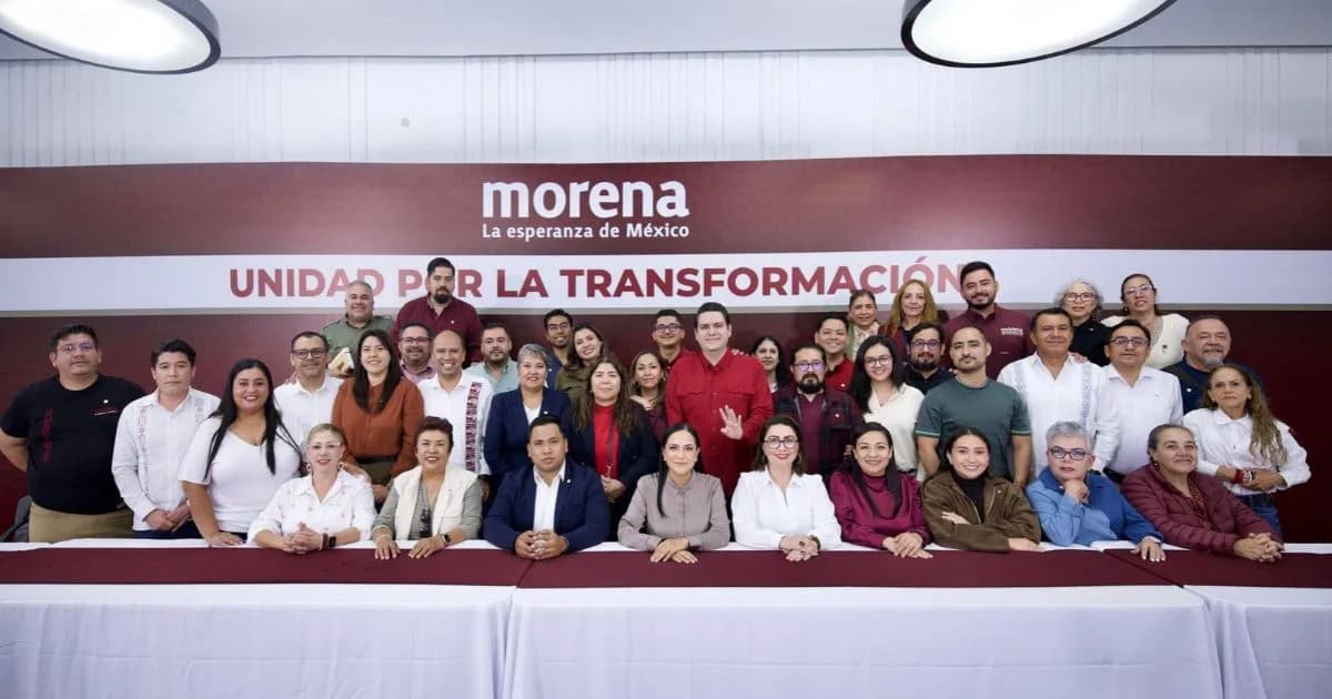 Grupo de personas reunidas para una fotografía frente al emblema de Morena y un letrero de unidad por la transformación