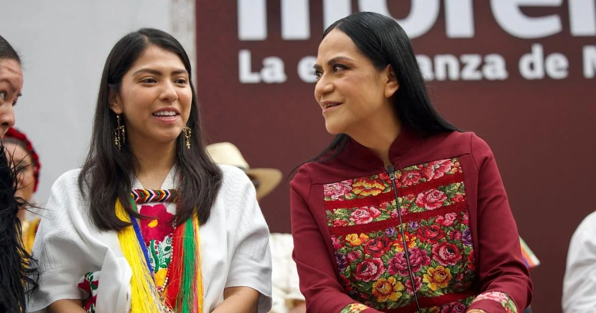 Ariadna Montiel y Bxido Jara conversan sentadas ante un fondo con el emblema de Morena durante el Primer Encuentro Nacional de Pueblos Indígenas y Afromexicanos de Morena