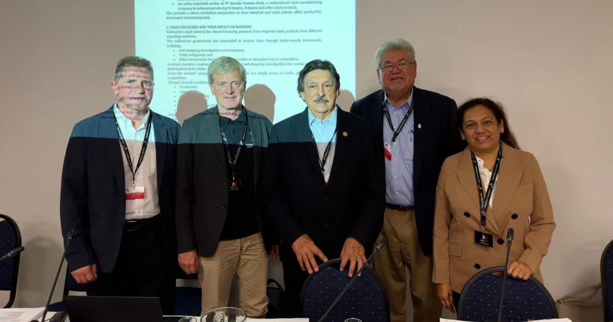Cinco participantes posan frente a una proyección durante una conferencia sindical internacional
