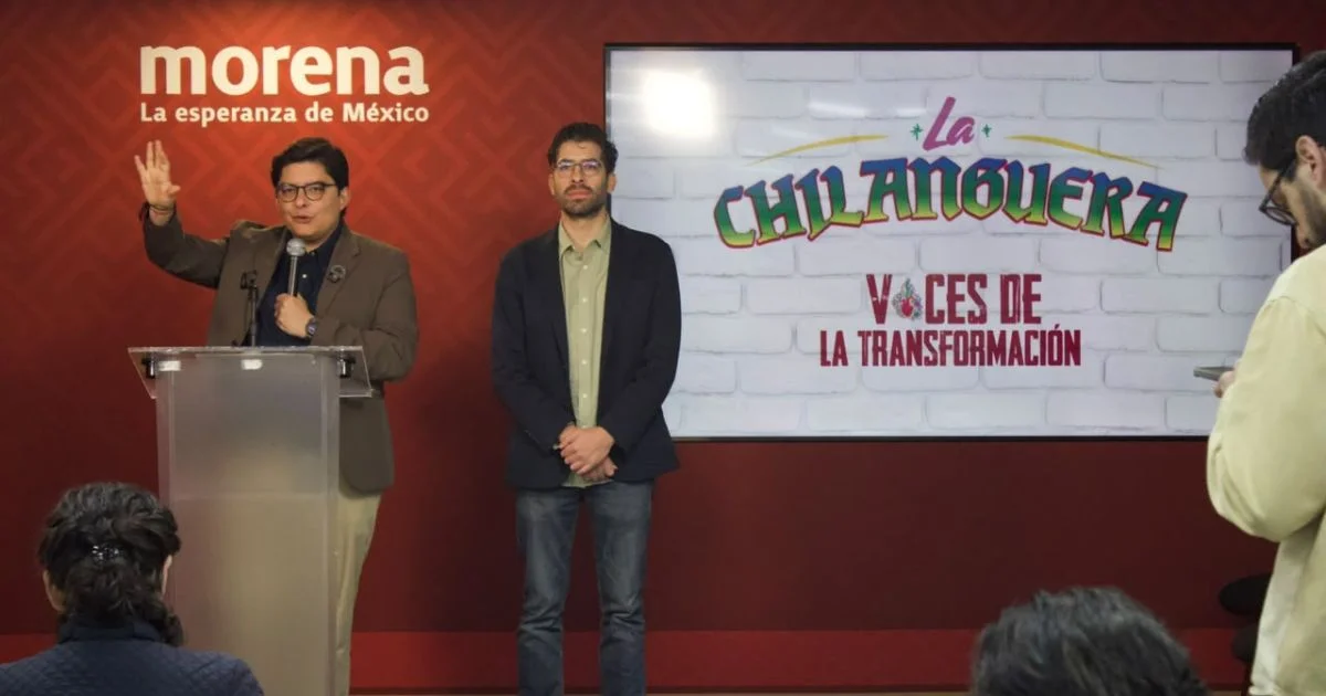 Conferencia de Morena con un orador frente al micrófono y otra persona junto a una pantalla de La Chilanguera