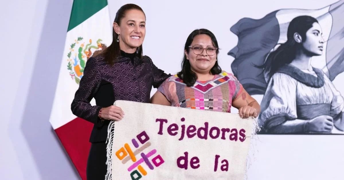 Dos mujeres sostienen un textil con la frase “Tejedoras de la Patria” frente a una bandera de México y una ilustración