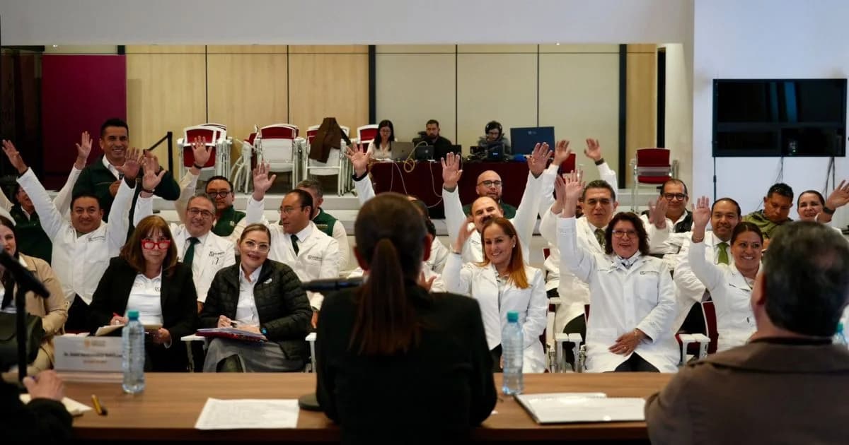 Personal médico y directivos de hospitales con batas blancas levantan las manos durante una reunión en un auditorio